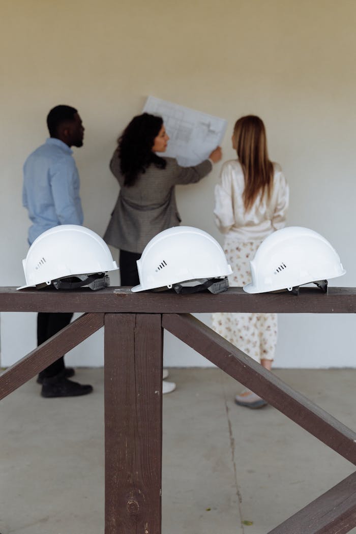 Group of architects discussing construction plans with hard hats in focus.